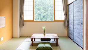 A traditional Japanese room with tatami flooring, a low table with a vase, and a sliding door.