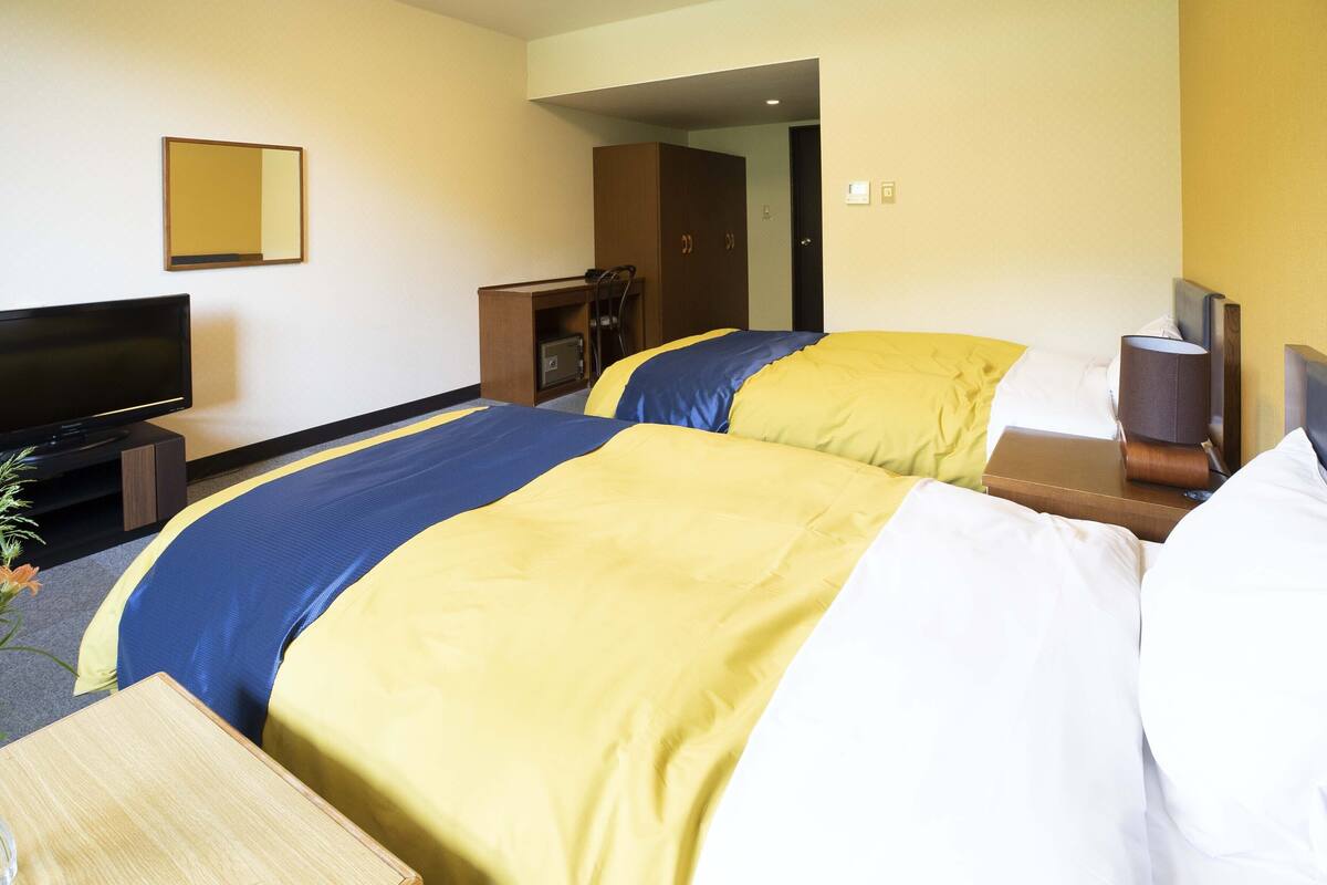 A hotel room with two beds, a television, a desk, and a wardrobe.