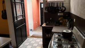 A compact kitchen with a gas stove, a sink, and a window overlooking a street. - Casa Azul (Guatemala City)