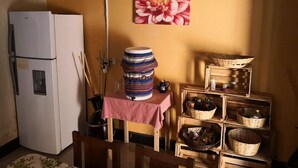 A compact kitchen with a white refrigerator, a table with a red checkered tablecloth, and wooden crates with baskets. - Casa Azul (Guatemala City)