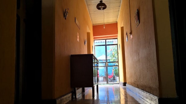 A hallway with a tiled floor, a bench, and a door leading to an outdoor area with a view of greenery. - Casa Azul (Guatemala City)