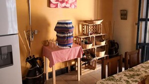 A kitchen with a table set for dining, a refrigerator, and a shelf with baskets. - Casa Azul (Guatemala City)