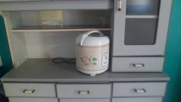 A kitchen area with a white electric kettle on a grey countertop, a microwave above it, and a grey cabinet with a glass door.