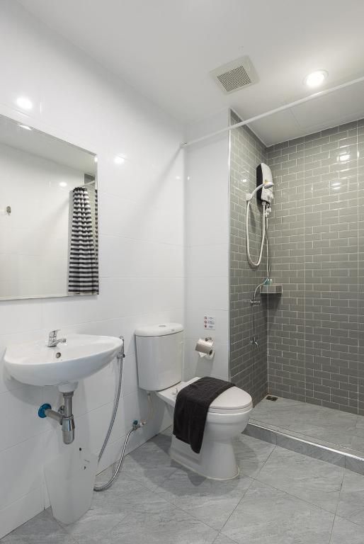 A modern bathroom with a white sink, toilet, and shower.