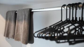 Ein Metallstab mit einem darüberliegenden Stoff, an der Wand befestigt durch eine Reihe schwarzer Kleiderbügel.