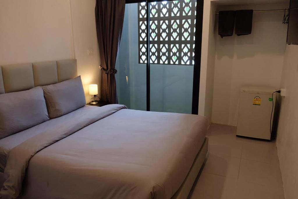 A bedroom with a bed, a nightstand, a window with a view, and a small refrigerator.
