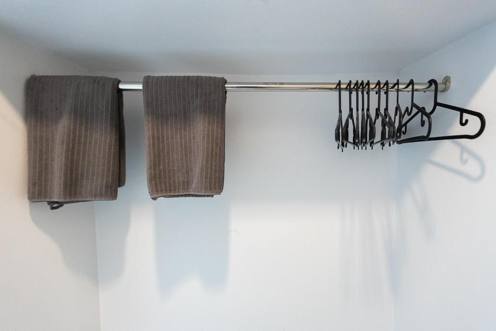 A wall-mounted towel rack with two towels and a hanger with multiple hangers.