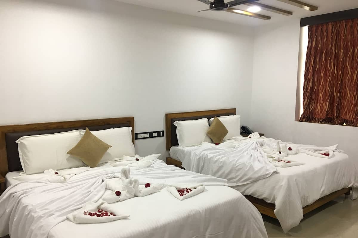 A hotel room with two beds, each with white linens and decorative pillows.