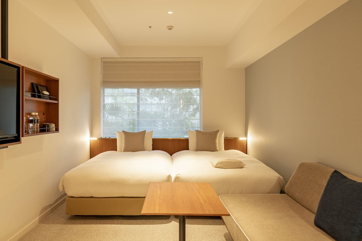 Una habitación de hotel moderna con una cama grande, una mesita y un sofá.