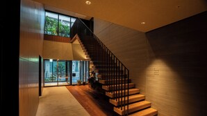 Un interior moderno con una escalera de madera, ventanas amplias y vistas al exterior.