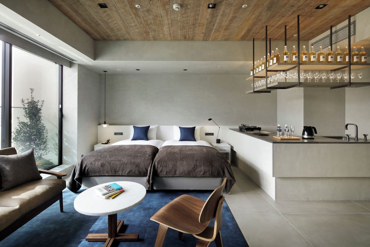 Una habitación de hotel moderna con cama, sofá, mesa de comedor y área de cocina.
