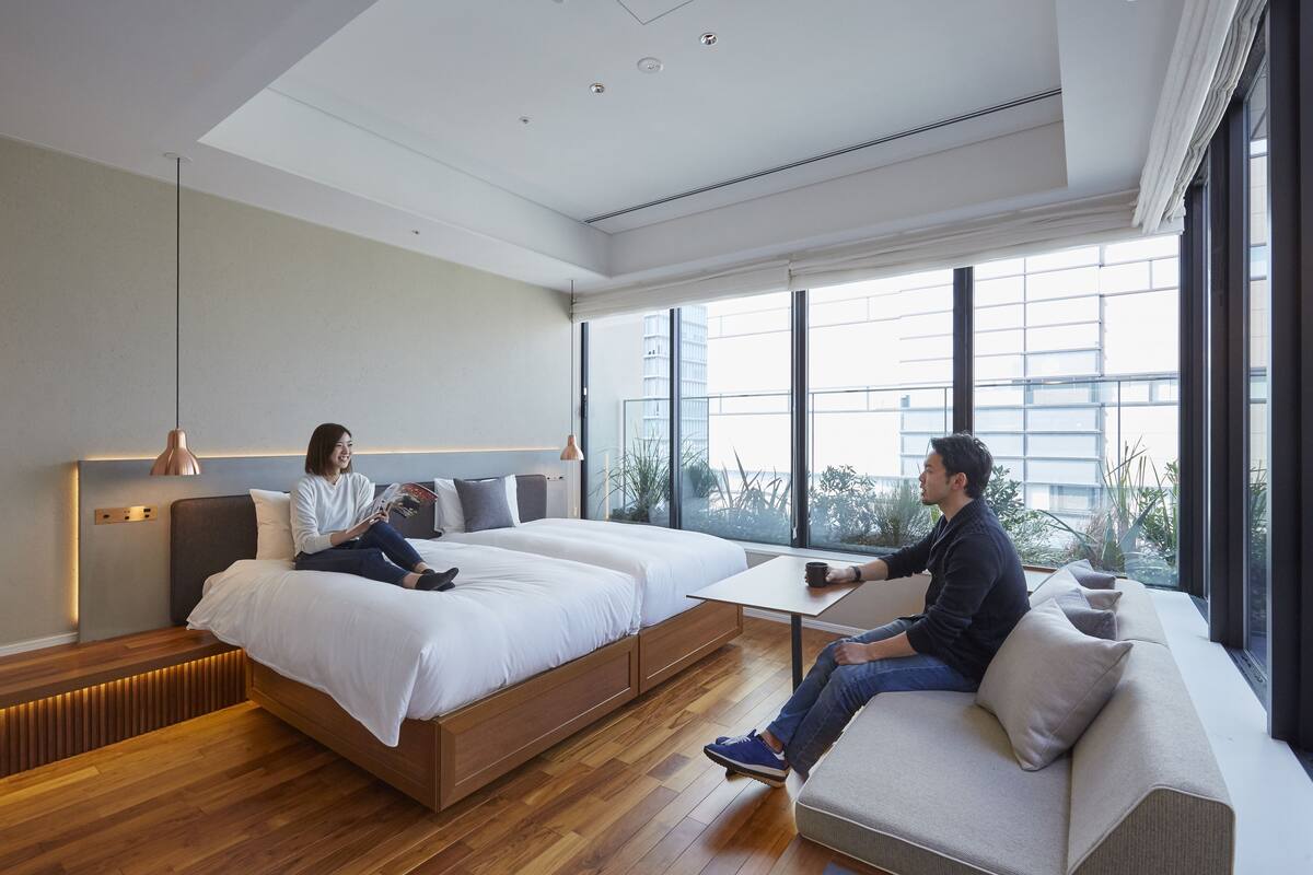 Habitación de hotel moderna con una cama grande, un sofá y una mesita. Amplias ventanas con vista a la ciudad.