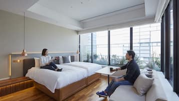 Habitación de hotel moderna con una cama grande, un sofá y una mesita. Amplias ventanas con vista a la ciudad.