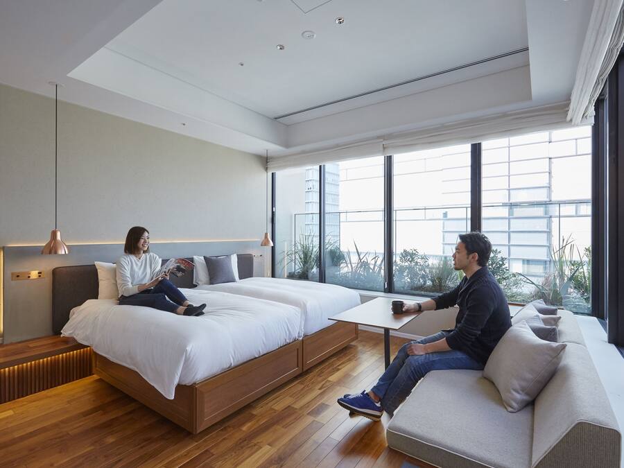 Habitación de hotel moderna con una cama grande, un sofá y una mesita. Amplias ventanas con vista a la ciudad.