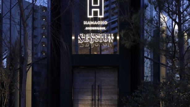 Un edificio moderno con un llamativo letrero en forma de 'H' y el nombre 'SESSIONS' en la fachada.