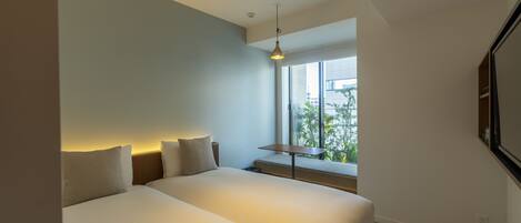 Ein modernes Hotelzimmer mit einem großen Bett, einem kleinen Tisch und einem Fenster mit Blick auf Grünflächen.