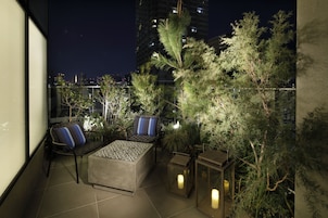 An outdoor terrace with seating, plants, and lanterns.