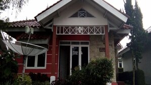 Un edificio de dos pisos con fachada roja y blanca, un pequeño porche y una antena parabólica.