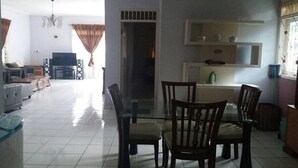 Una sala de estar con televisor, asientos y un comedor con sillas y mesa.