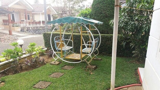 Un jardín con un columpio, un pequeño pabellón y un césped bien cuidado.