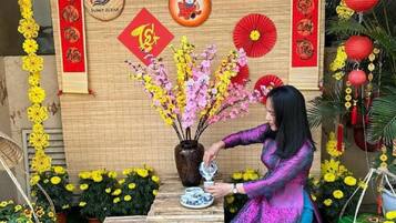 A woman arranging flowers in a vase on a wooden table in a decorated room with traditional Chinese elements.