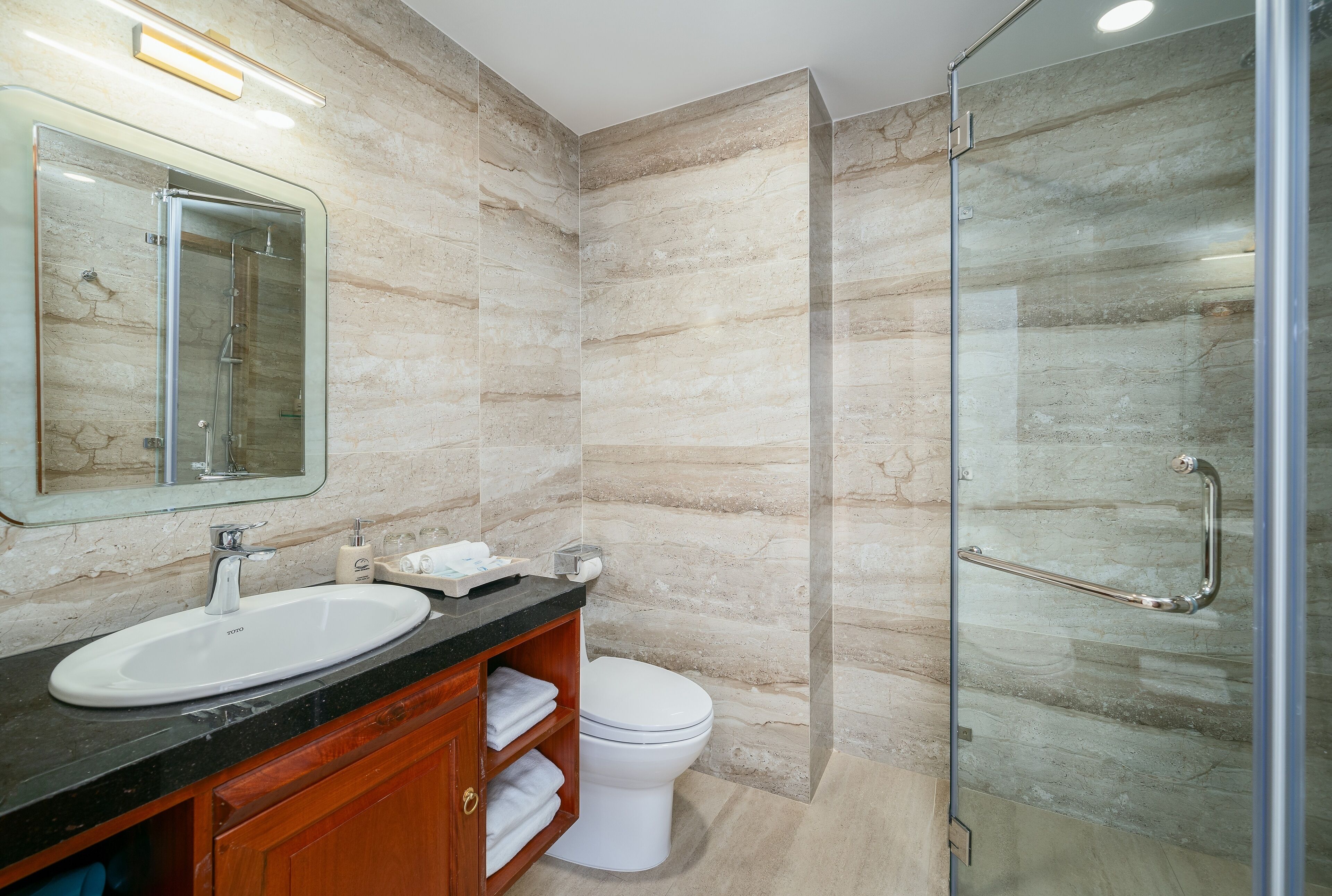 A modern bathroom with a glass shower enclosure, a white sink, and a wooden vanity.