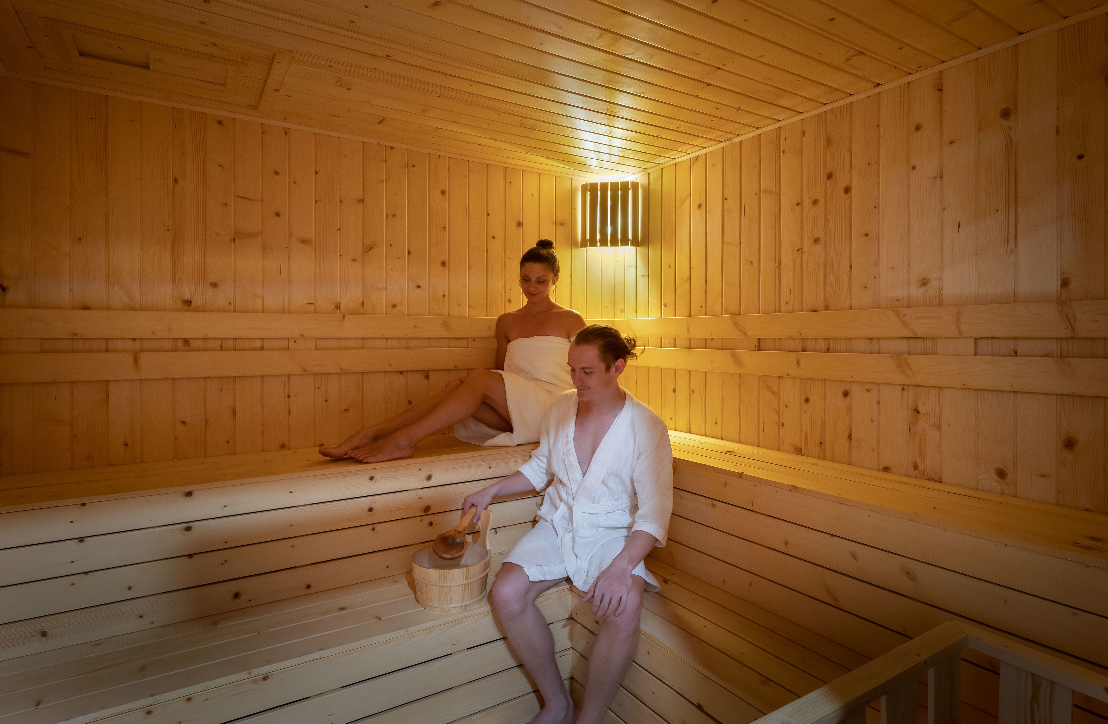 En träbeklädd bastu med sittbänkar och en träspänd hink.