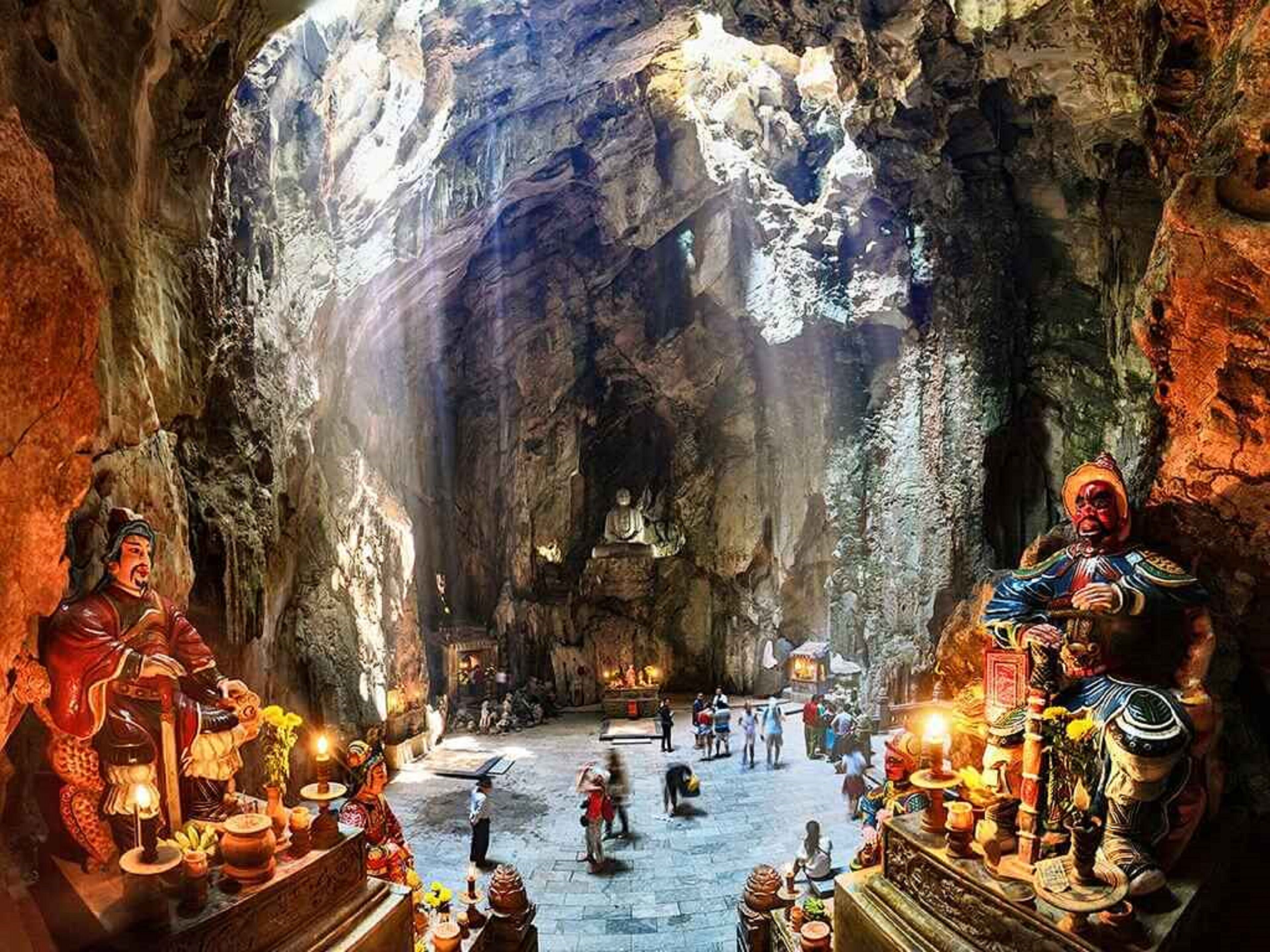 A cave interior with statues and visitors.