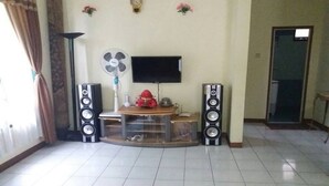 Una sala de estar con televisión, dos parlantes, un ventilador y una mesita con adornos.