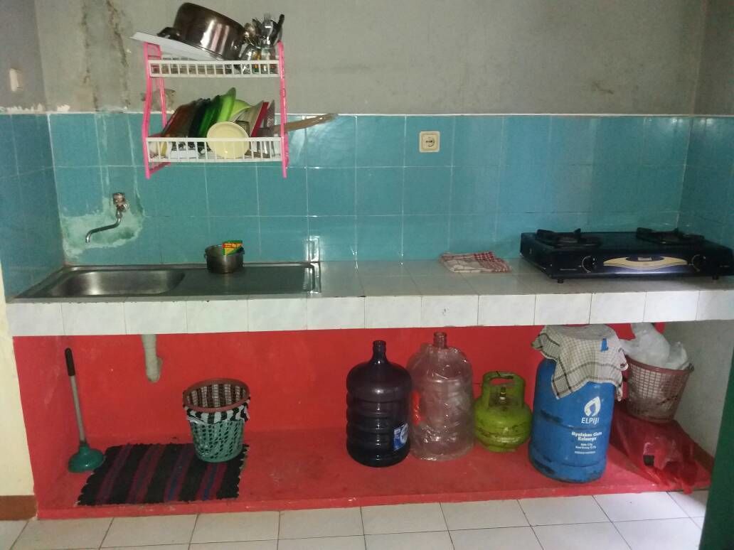 A kitchen with a sink, a shelf with dishes, a gas stove, and various containers on the counter.