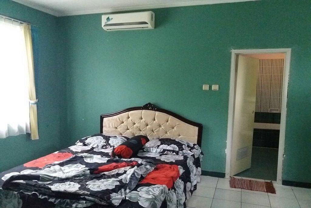 Une chambre à coucher avec un lit, un climatiseur, une porte et une fenêtre avec des rideaux.