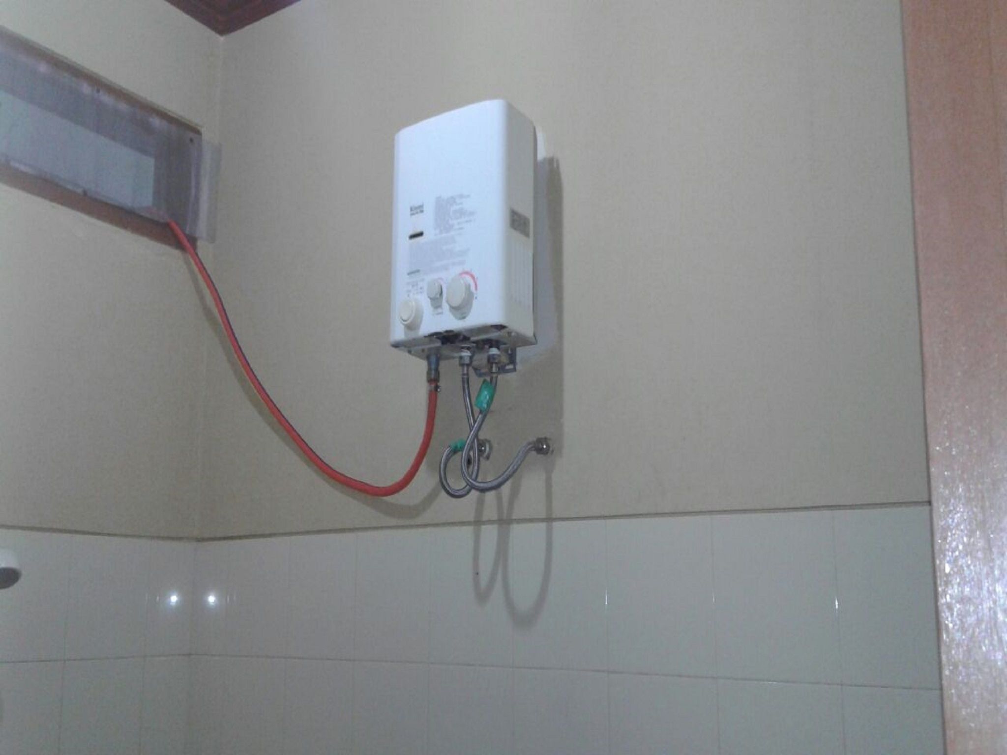 A white electrical box mounted on a wall with a red wire connected to it.