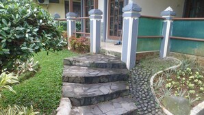 A stone staircase leading to a building entrance, surrounded by well-maintained greenery and a small garden area.