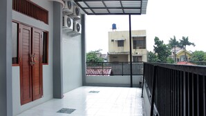 Ein Balkon mit Fliesenboden, schwarzem Geländer und Blick auf Gebäude im Hintergrund.