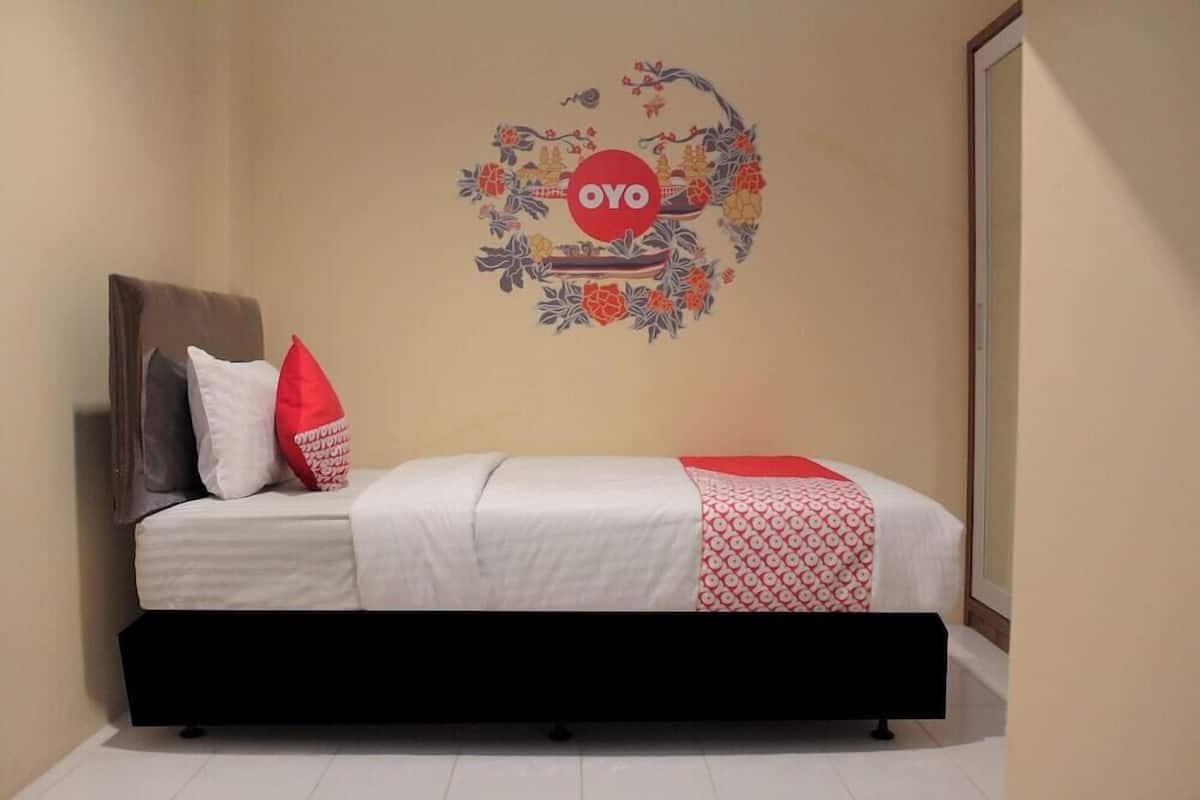 Ein Schlafzimmer mit einem Bett, Kissen, einer Wanddekoration und einem Kleiderschrank.