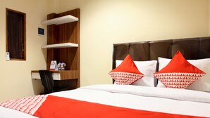 Ein Hotelzimmer mit einem Bett, einer Holzregaleinheit und einem Schreibtisch mit Stuhl.