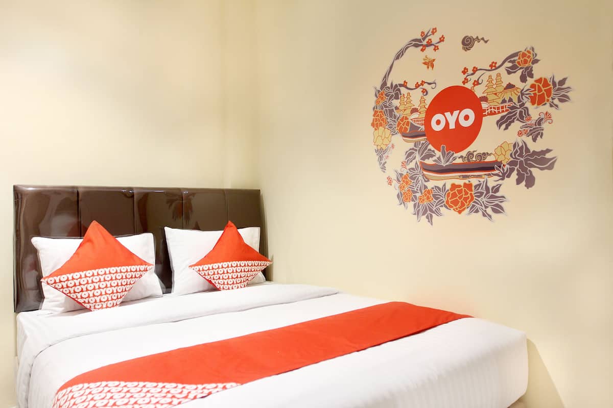 Ein Hotelzimmer mit einem Bett, zwei Kissen, einem Kopfteil und einer Wanddekoration.