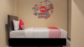 A bedroom with a bed, pillows, a wall decoration, and a mirror.