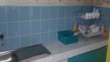 A kitchen with teal cabinets, a sink, and a dish rack on the countertop.