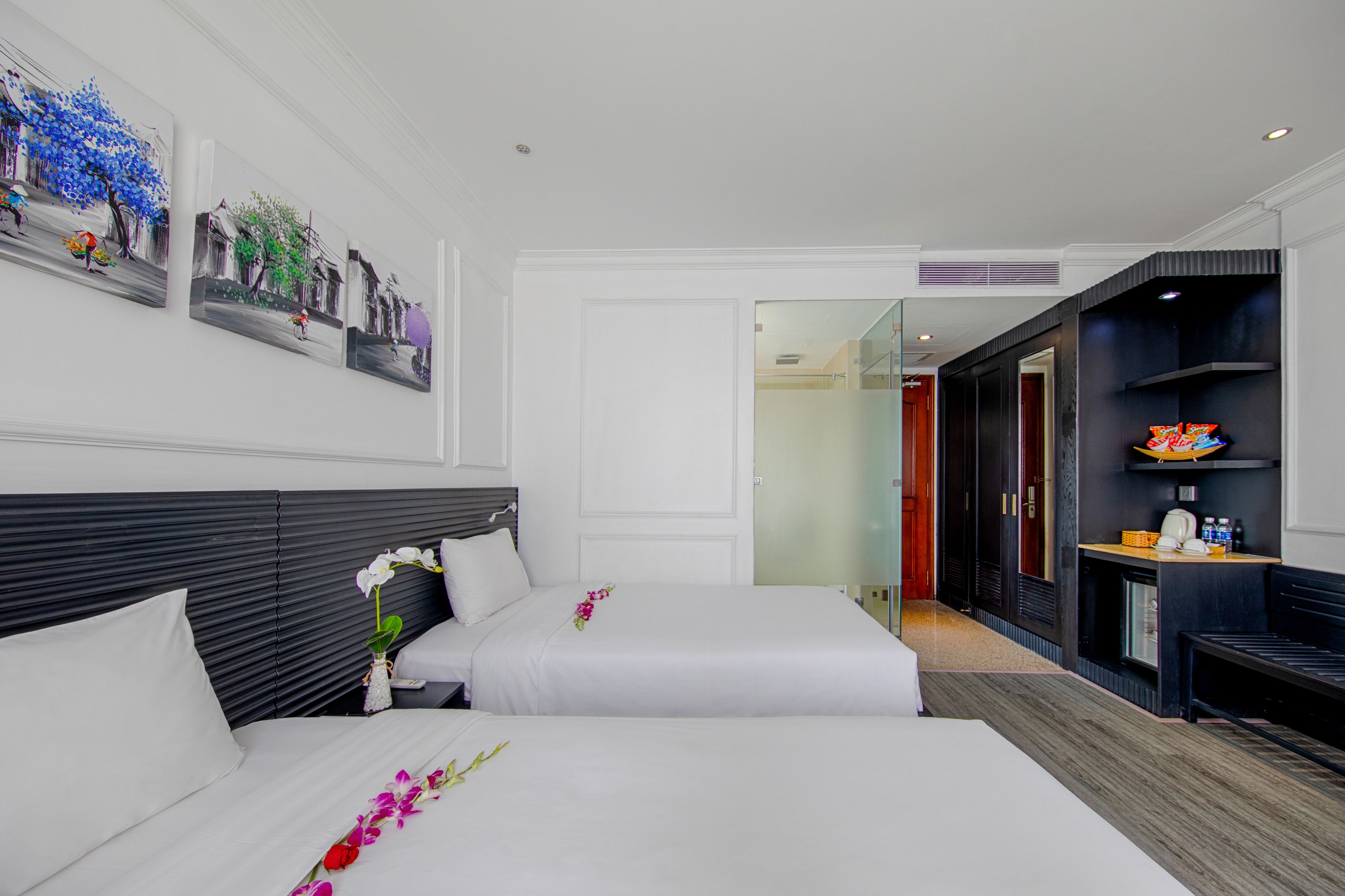 A hotel room with two beds, a large mirror, and artwork on the wall.
