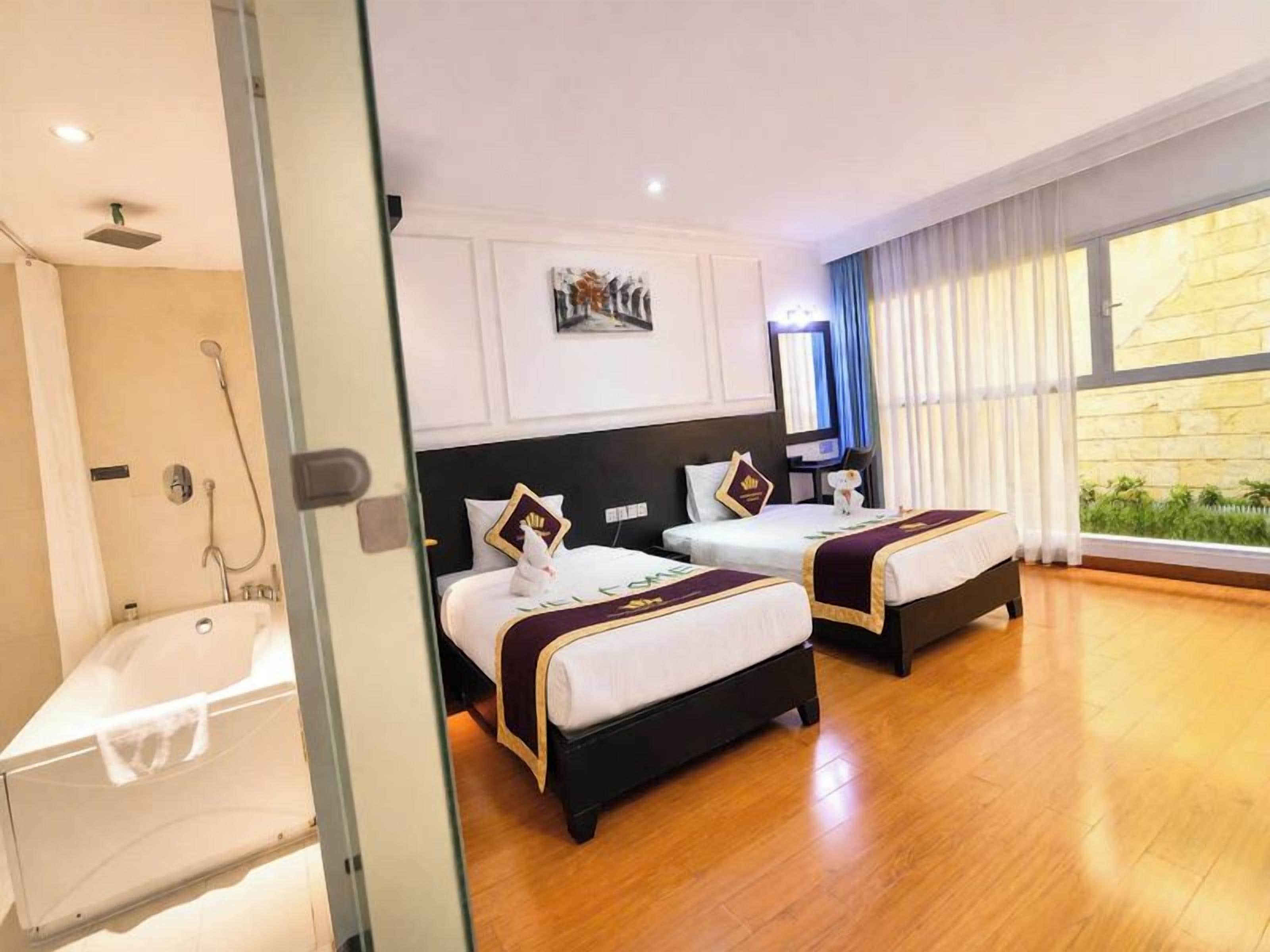 Une chambre d’hôtel avec deux lits, une baignoire et une grande fenêtre avec des rideaux.