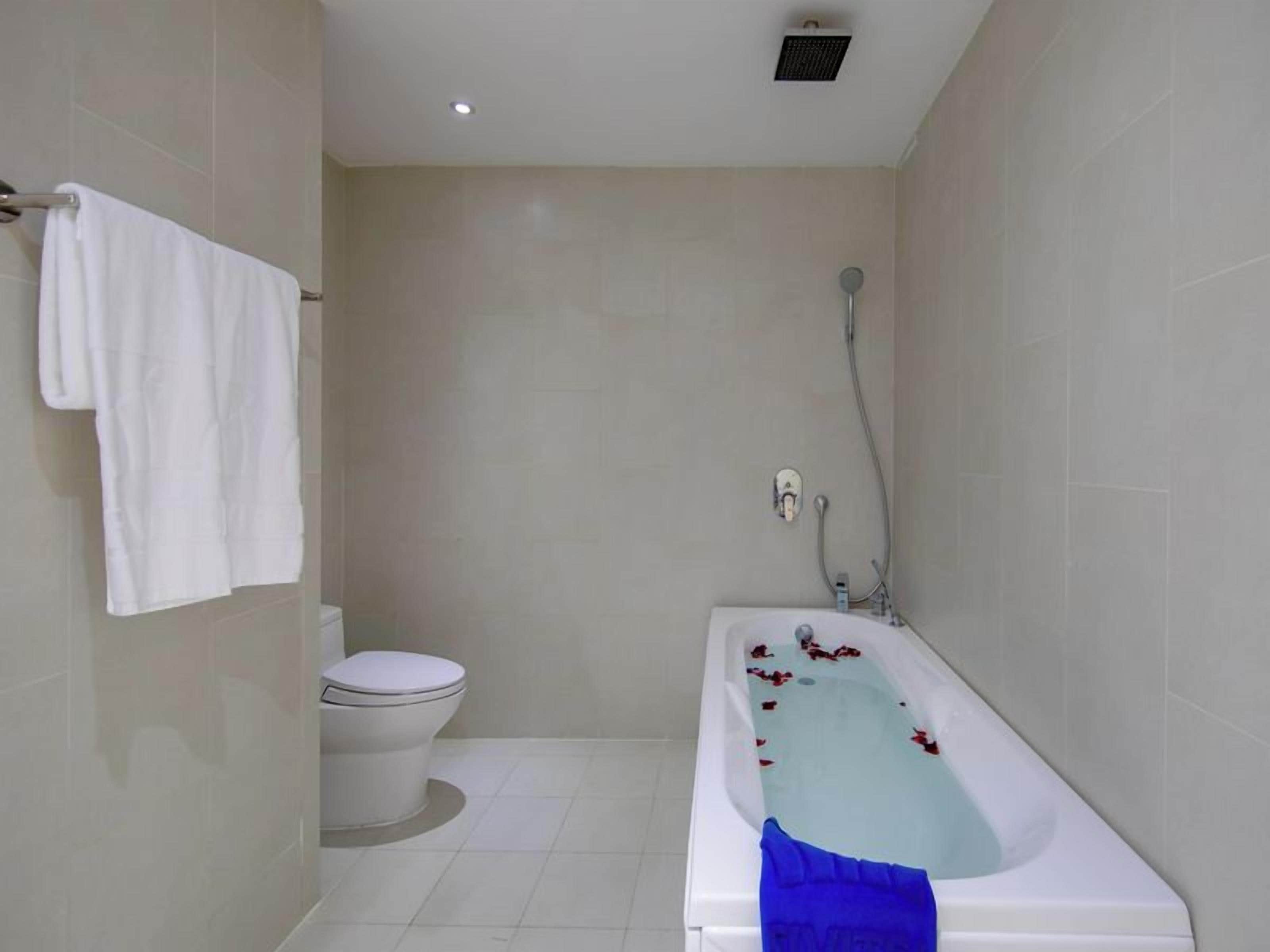 A bathroom with a bathtub, toilet, and a towel rack.