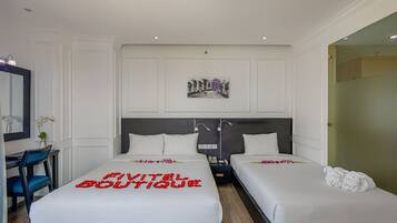 A hotel room with two beds, a desk, and a mirror.