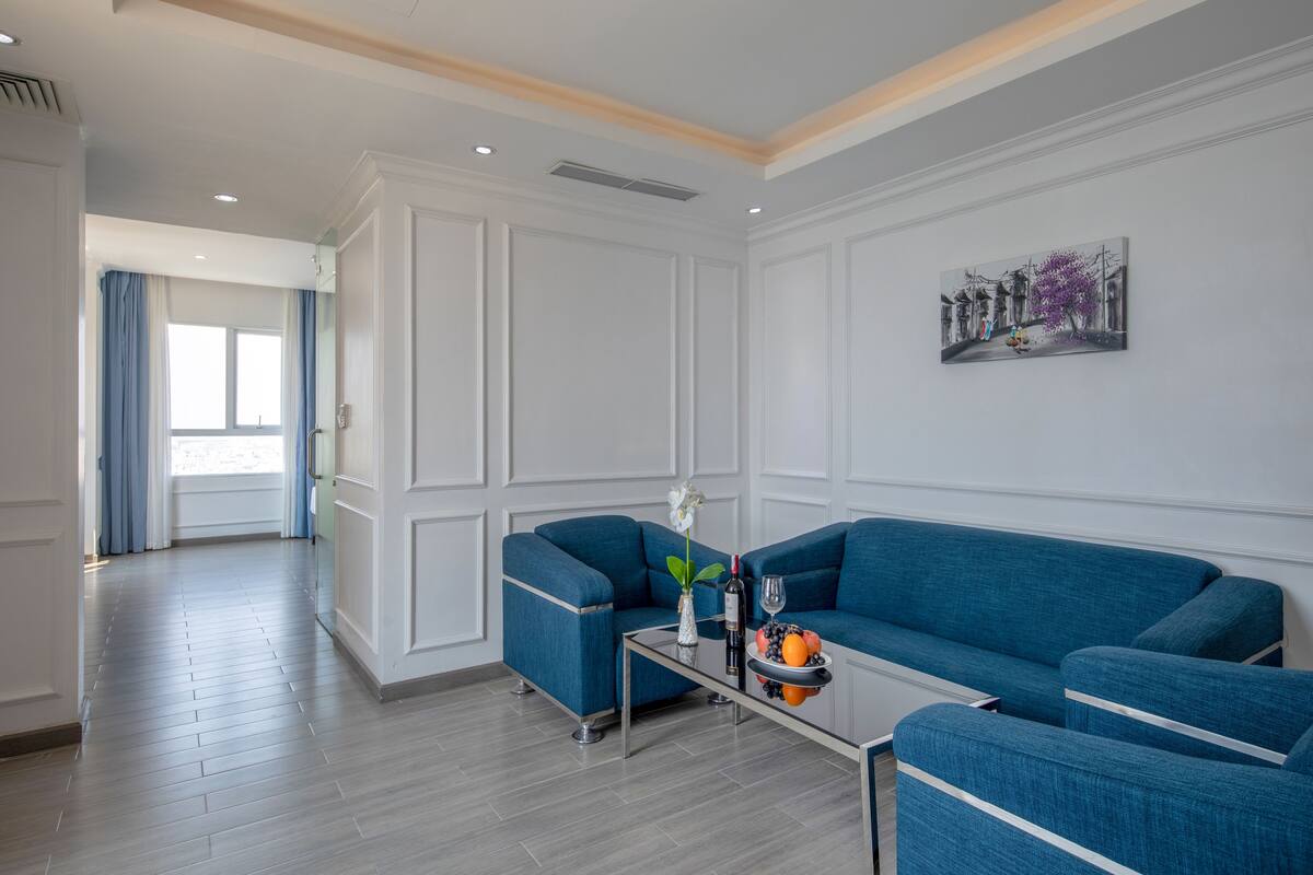 Una sala de estar moderna con dos sofás azules, una mesa de centro de vidrio y un cuadro en la pared.