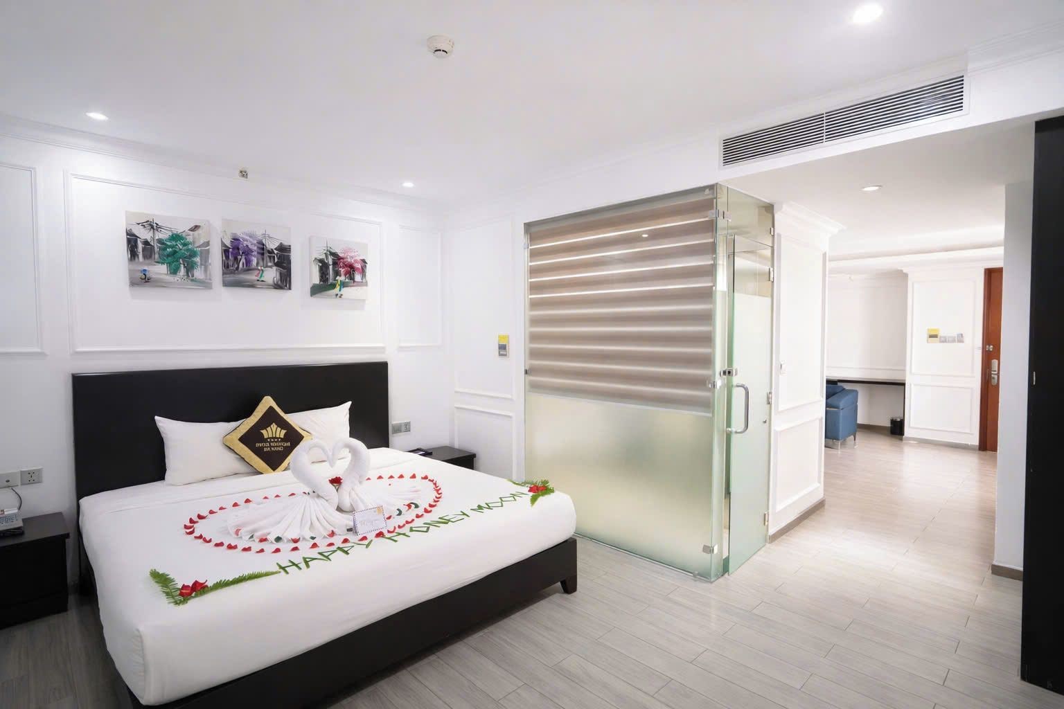 A hotel room with a bed, a bedside table, a wall-mounted artwork, and a sliding door leading to a bathroom.