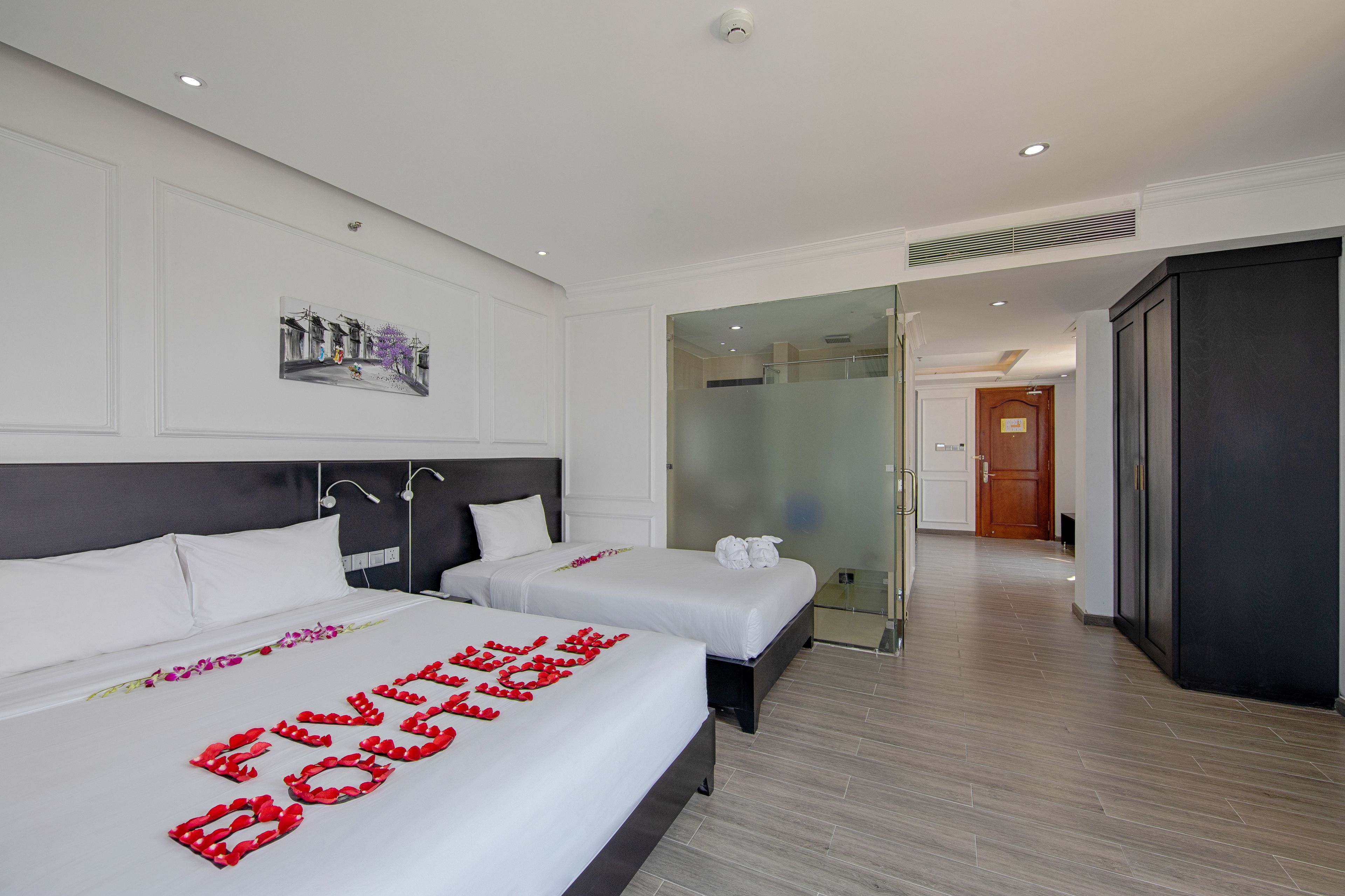 Habitación de hotel con dos camas, un ventanal grande y vista a la calle.