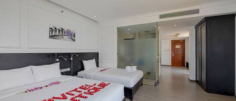 Habitación de hotel con dos camas, un ventanal grande y vista a la calle.