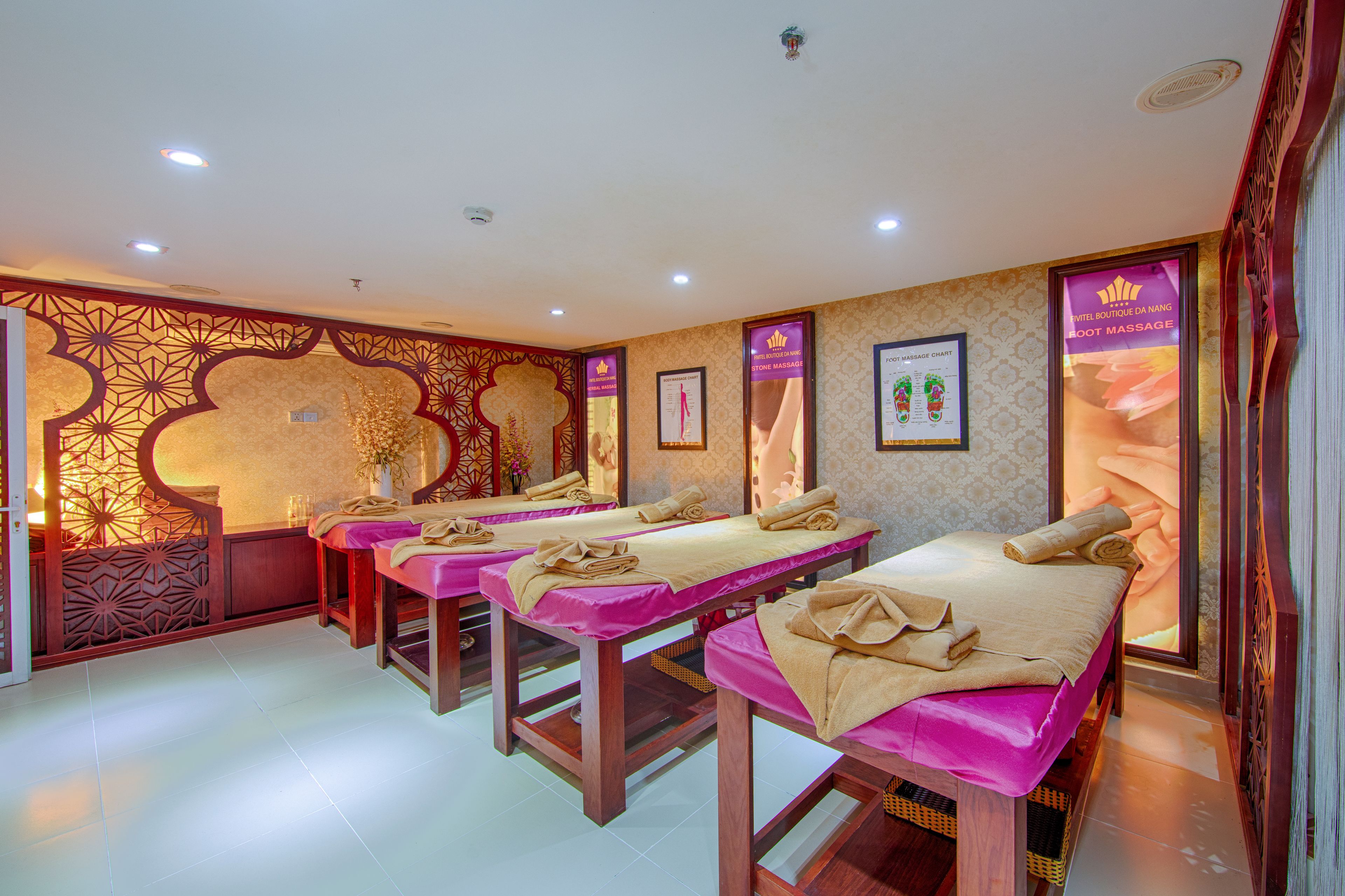 A spa room with multiple massage tables, each with towels and a foot massage poster.