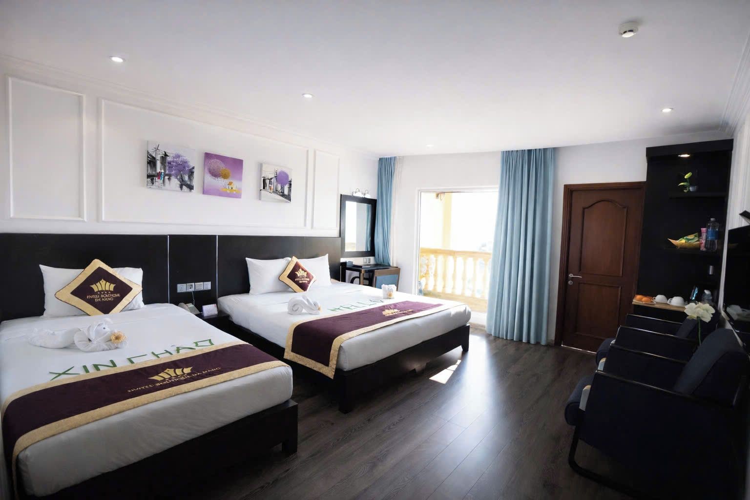 A hotel room with two beds, a desk, a chair, a TV, and a balcony.