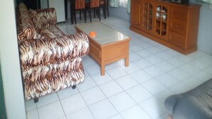 Een woonkamer met een bank, een salontafel, een televisie en een kast.